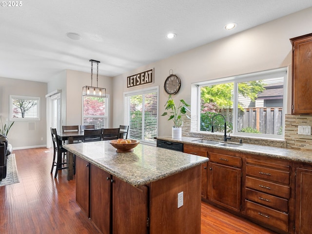 kitchen with backsplash, a kitchen island, a sink, and plenty of natural light