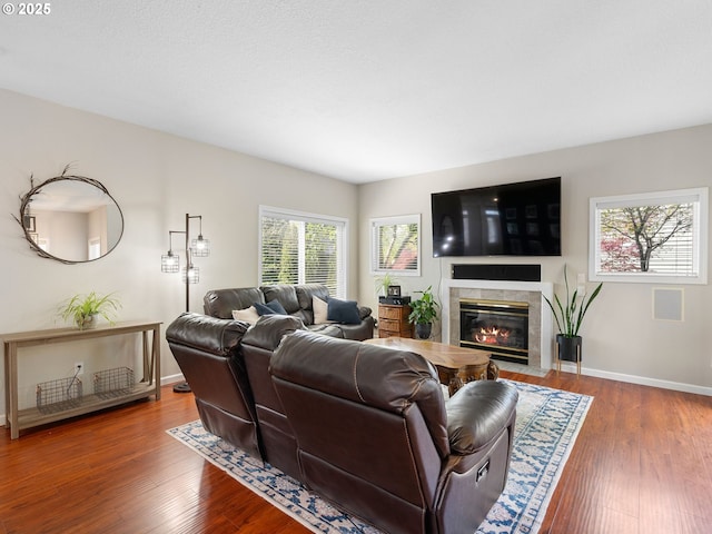 living area featuring baseboards, wood finished floors, and a high end fireplace