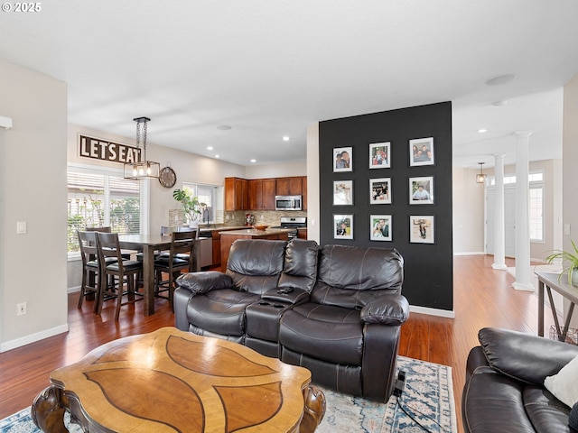 living area with baseboards, decorative columns, recessed lighting, and light wood-style flooring