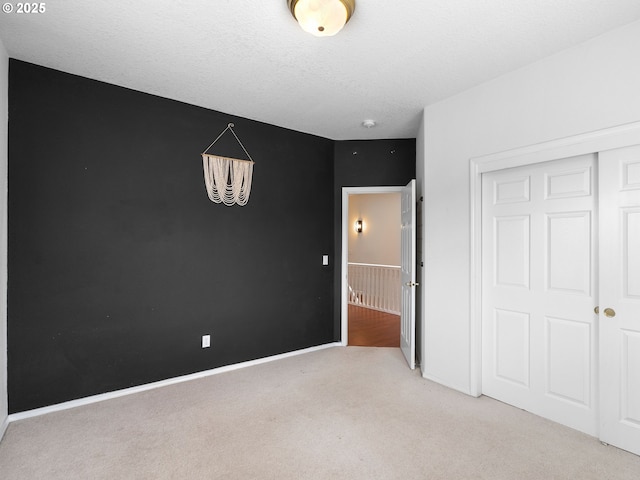 unfurnished bedroom featuring a closet, baseboards, a notable chandelier, and light carpet