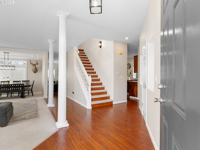 foyer featuring stairway, baseboards, ornate columns, and wood finished floors