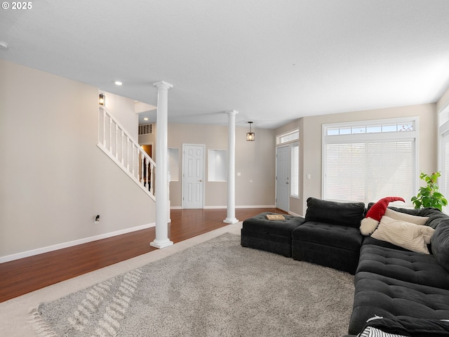 living area with decorative columns, stairs, wood finished floors, and visible vents