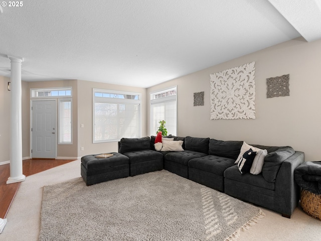 living room featuring ornate columns, carpet, and baseboards