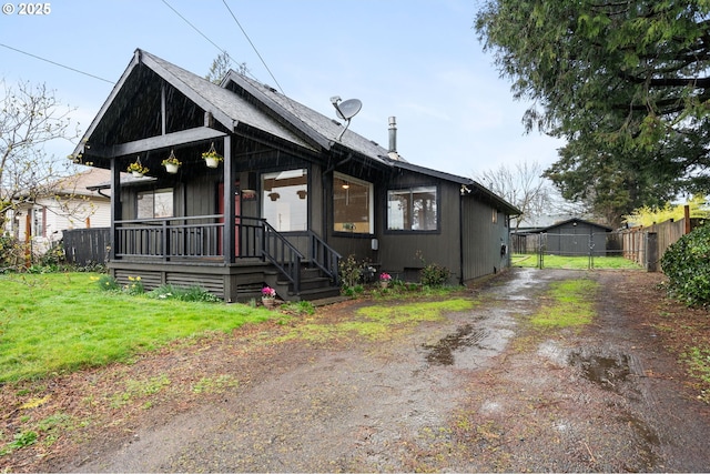 view of front of property featuring a gate, dirt driveway, fence, covered porch, and a front yard