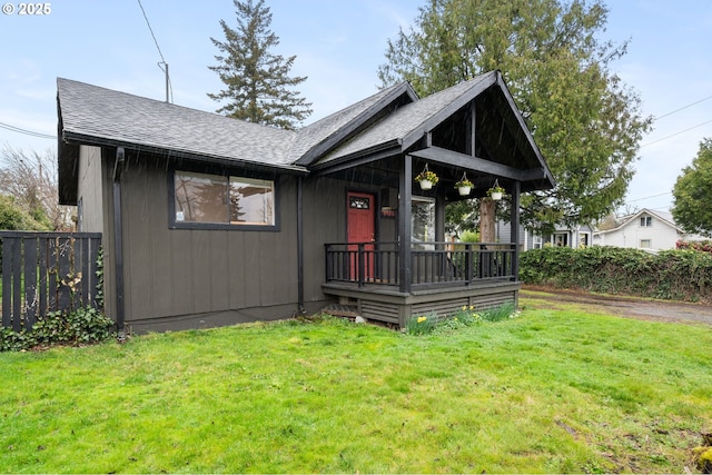 view of front facade with fence, a front lawn, and a shingled roof