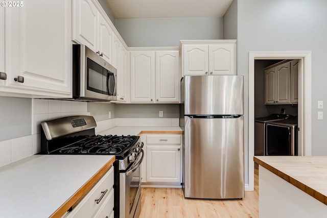 4675 Symphony Dr, Eugene, OR 97404 - kitchen with stainless steel appliances, separate washer and dryer, white cabinetry, light wood finished floors, and butcher block countertops