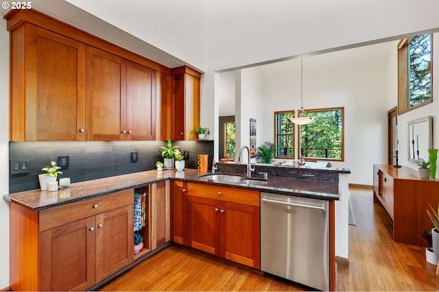 kitchen featuring a sink, light wood finished floors, stainless steel dishwasher, and a peninsula
