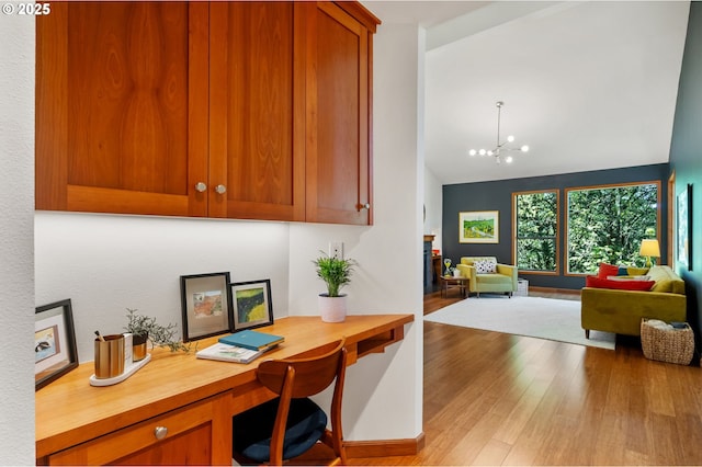 home office with a chandelier, light wood-style flooring, and lofted ceiling
