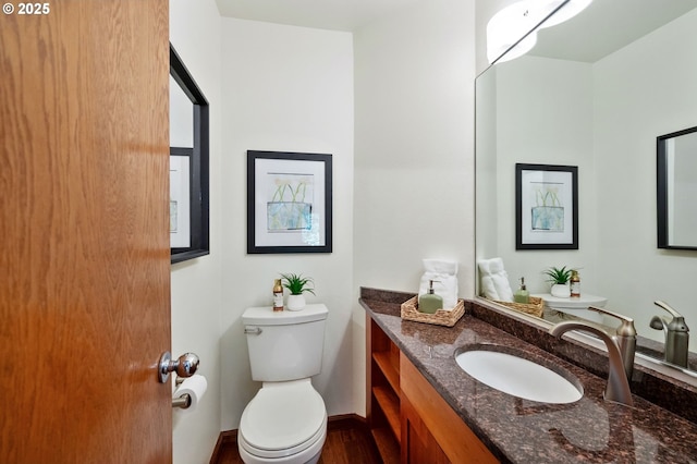 bathroom featuring toilet, baseboards, wood finished floors, and vanity