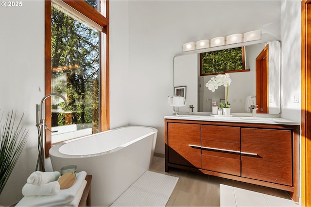 full bath featuring double vanity, tile patterned floors, and a freestanding bath