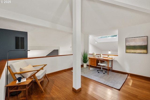 office space featuring vaulted ceiling with skylight, recessed lighting, baseboards, wood finished floors, and visible vents