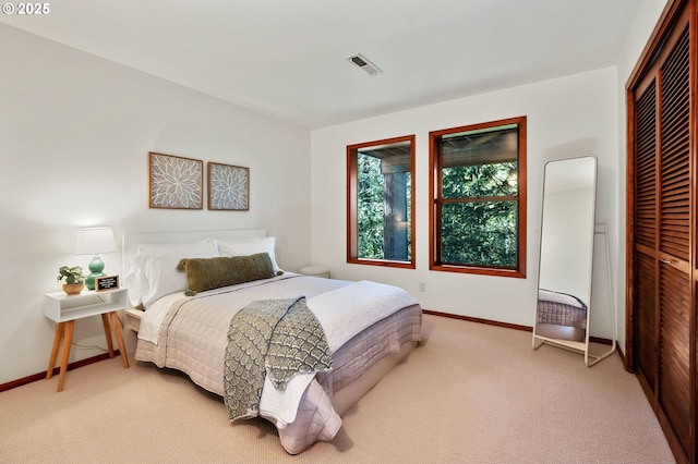 bedroom with visible vents, baseboards, a closet, and light carpet