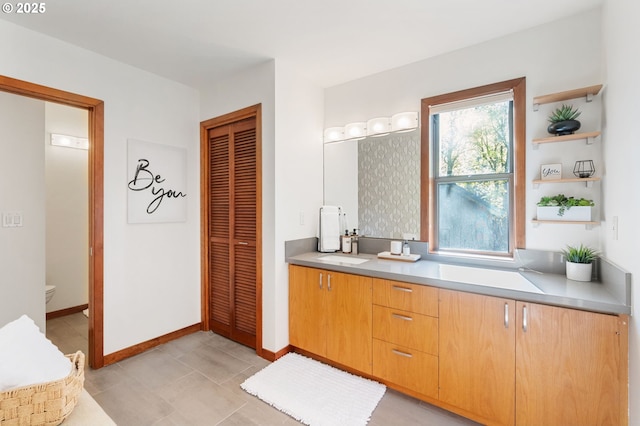 full bath featuring vanity, baseboards, a closet, and toilet