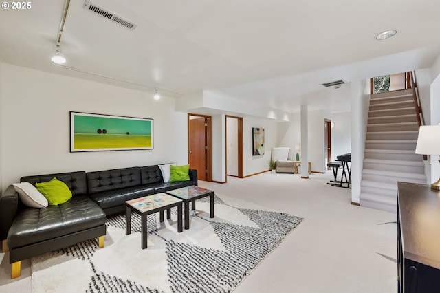 carpeted living area with stairway, rail lighting, and visible vents