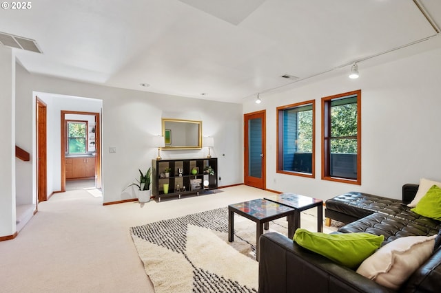 living area with carpet floors, baseboards, visible vents, and track lighting