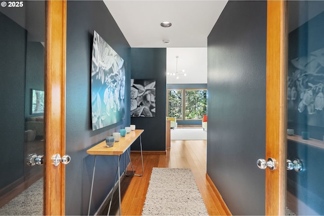 hall with a notable chandelier and wood finished floors