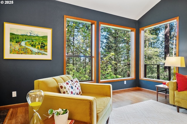 sitting room with baseboards, vaulted ceiling, and wood finished floors
