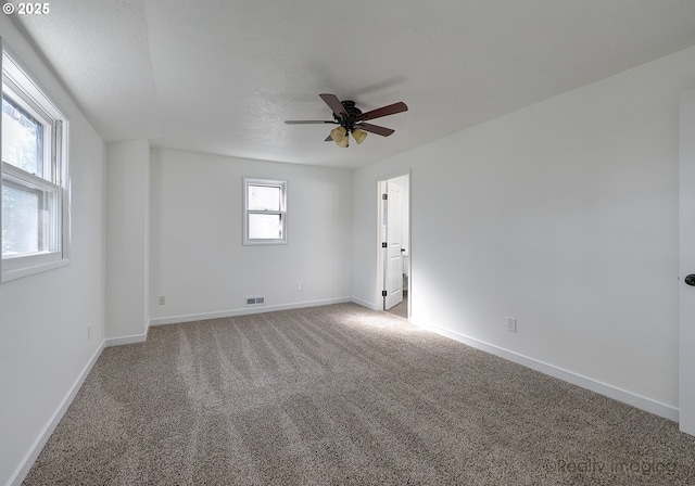 unfurnished room featuring light carpet, visible vents, baseboards, ceiling fan, and a textured ceiling