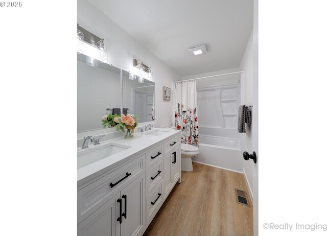 full bathroom with visible vents, toilet, wood finished floors, shower / bathtub combination with curtain, and a sink