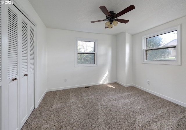 unfurnished bedroom with carpet floors, multiple windows, and baseboards