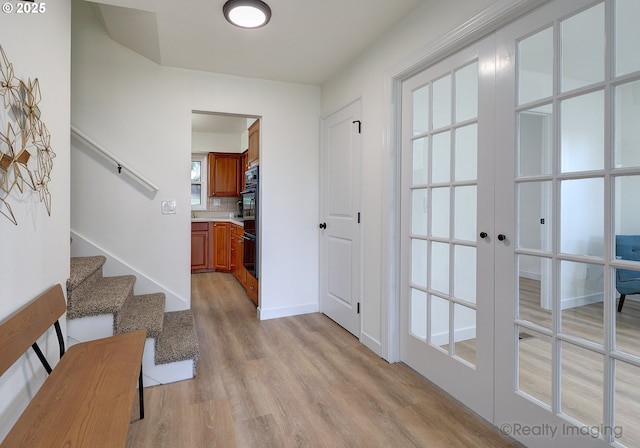 interior space with stairs, french doors, light wood finished floors, and baseboards