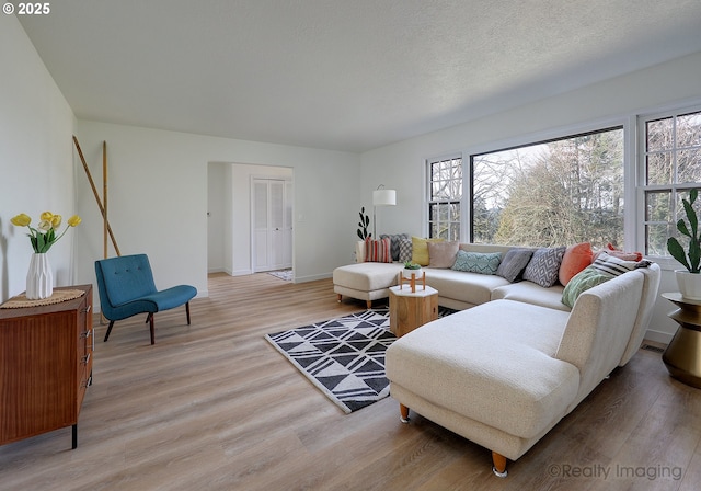 living room with light wood-style flooring, baseboards, and a textured ceiling