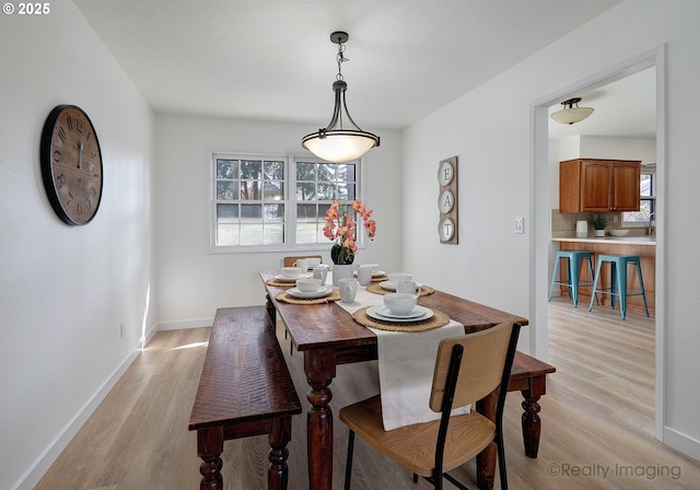 dining area featuring light wood-type flooring and baseboards