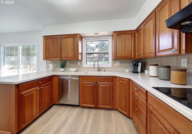 kitchen with a peninsula, extractor fan, stainless steel dishwasher, light wood-style floors, and a sink