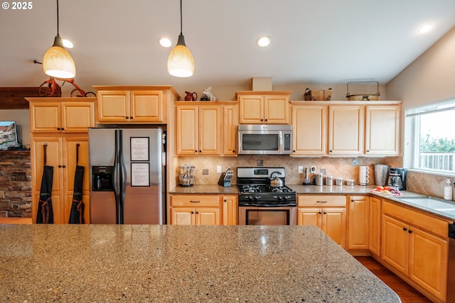 kitchen with appliances with stainless steel finishes, sink, backsplash, hanging light fixtures, and light stone countertops