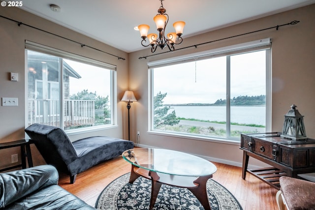 living area with a water view, plenty of natural light, light hardwood / wood-style flooring, and a notable chandelier