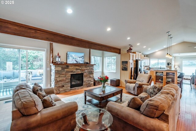 living room with vaulted ceiling, a fireplace, and light hardwood / wood-style floors