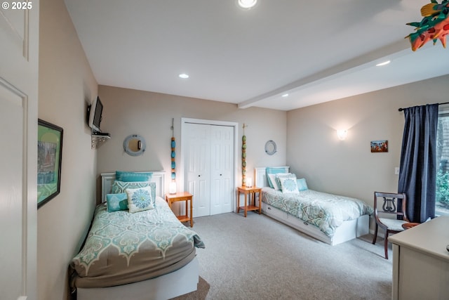 bedroom with carpet flooring, beam ceiling, and a closet