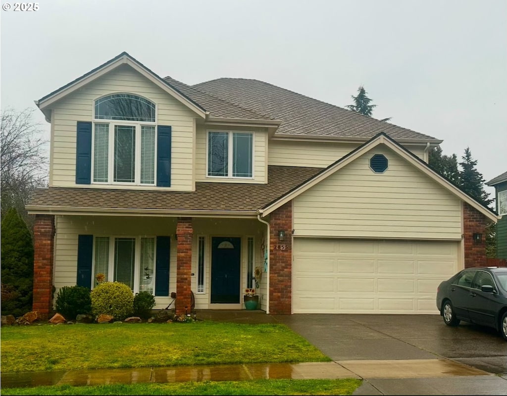 traditional-style house with roof with shingles, a porch, concrete driveway, a front yard, and a garage