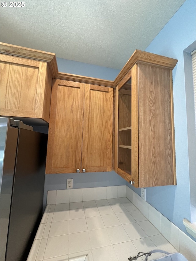 6230 SW Zabaco Ter, Beaverton, OR 97078 - kitchen featuring freestanding refrigerator, tile countertops, a textured ceiling, and brown cabinetry