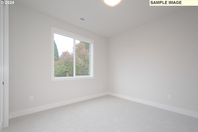 spare room featuring visible vents, baseboards, and light colored carpet