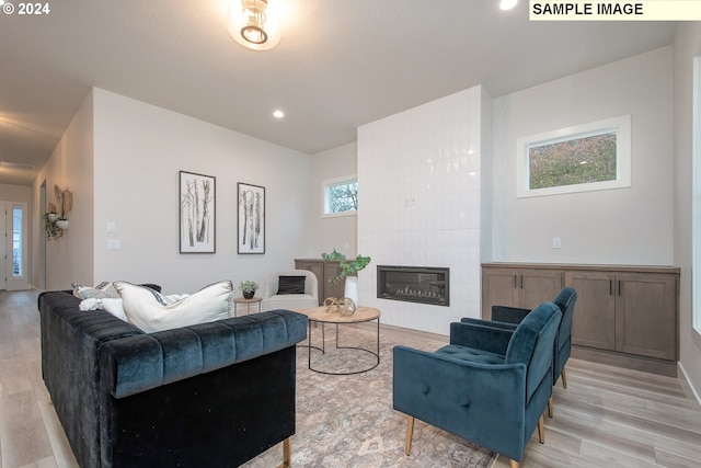 living room featuring light hardwood / wood-style flooring and a tiled fireplace