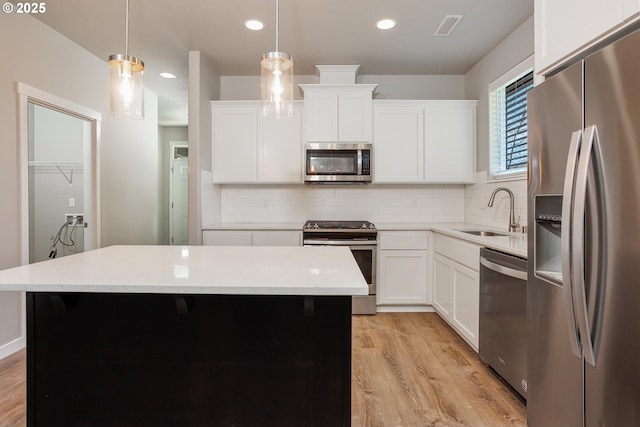 kitchen with decorative light fixtures, light countertops, visible vents, appliances with stainless steel finishes, and a sink