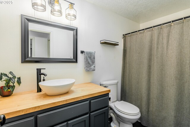 bathroom with a textured ceiling, toilet, and vanity