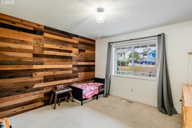 carpeted bedroom with wood walls and a textured ceiling