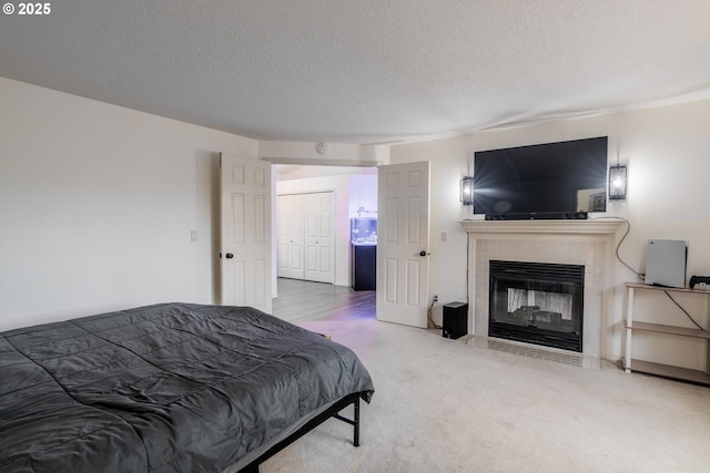 carpeted bedroom featuring a textured ceiling, a closet, and a tile fireplace