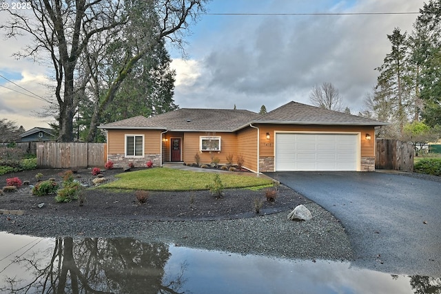 ranch-style home with stone siding, an attached garage, fence, and driveway