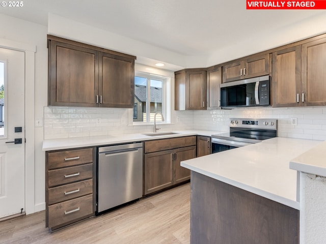 4578 NE Nicholson Loop, Vancouver, WA 98661 - kitchen with stainless steel appliances, a sink, light countertops, light wood finished floors, and tasteful backsplash