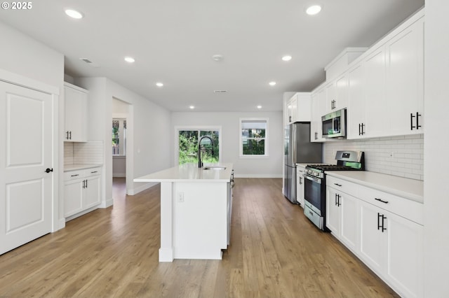 18315 SW Silvertip St, Beaverton, OR 97007 - kitchen featuring stainless steel appliances, a sink, a kitchen island with sink, backsplash, and baseboards