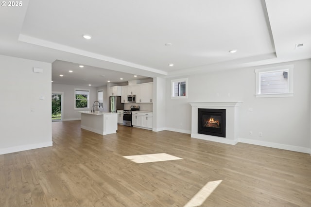 18315 SW Silvertip St, Beaverton, OR 97007 - unfurnished living room featuring a tray ceiling, a glass covered fireplace, baseboards, and recessed lighting