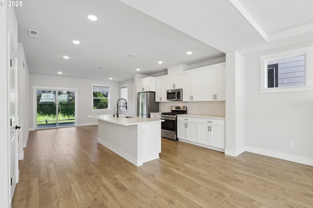 18315 SW Silvertip St, Beaverton, OR 97007 - kitchen featuring appliances with stainless steel finishes, tasteful backsplash, white cabinetry, a kitchen island with sink, and light countertops