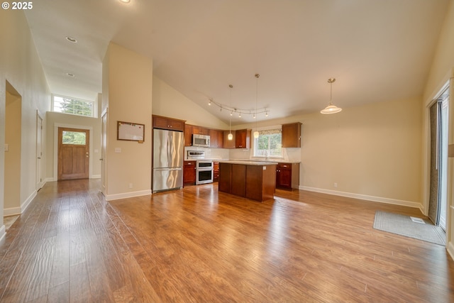 2639 Sykes Rd, Saint Helens, OR 97051 - kitchen with stainless steel appliances, open floor plan, wood finished floors, brown cabinetry, and a kitchen island