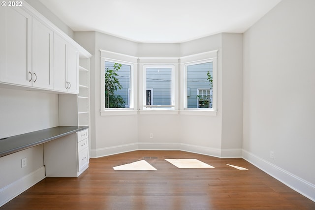 unfurnished room with hardwood / wood-style flooring and built in desk