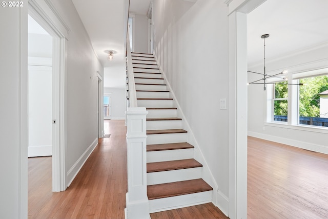 staircase with a chandelier and wood-type flooring