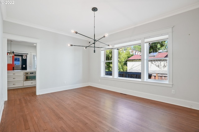 unfurnished room featuring wood-type flooring, crown molding, and a notable chandelier