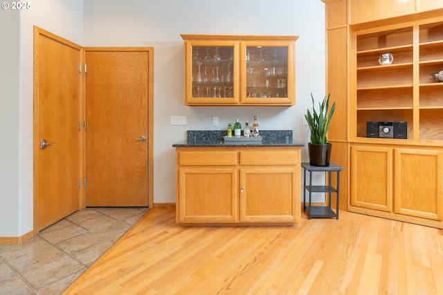 bar with light wood-type flooring, baseboards, and a bar